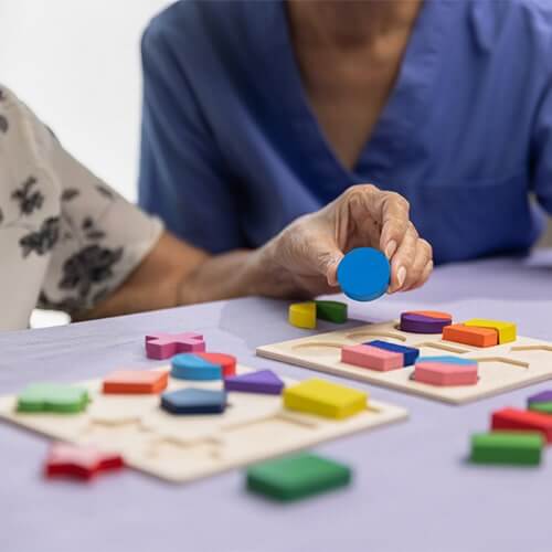 elderly woman playing wooden shape puzzle game